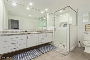 a bathroom with a granite countertop sink mirror and toilet