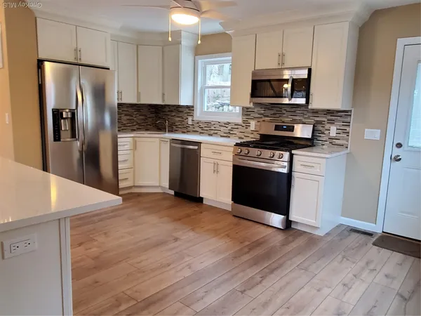 a kitchen with granite countertop a refrigerator stove and microwave