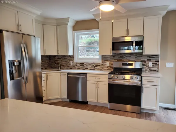 a kitchen with stainless steel appliances granite countertop a stove a refrigerator and a microwave