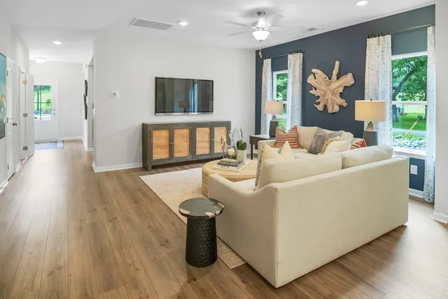 a living room with furniture a potted plant and a wooden floor