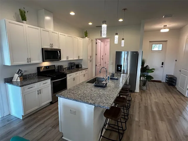 a kitchen with stainless steel appliances granite countertop a refrigerator a stove a sink and a microwave