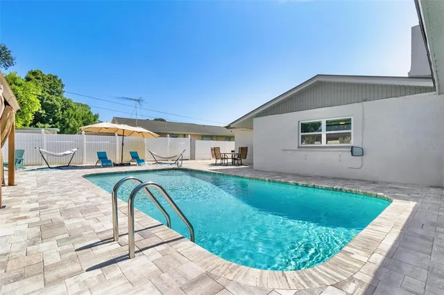 a view of backyard with swimming pool and furniture