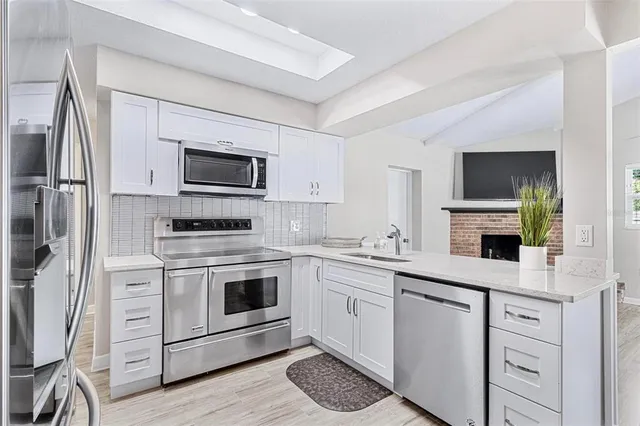 a kitchen with cabinets stainless steel appliances a sink and wooden floor