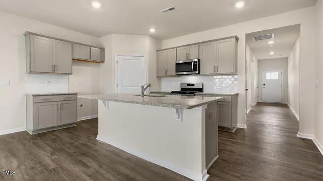 a kitchen with sink a microwave a stove and cabinets