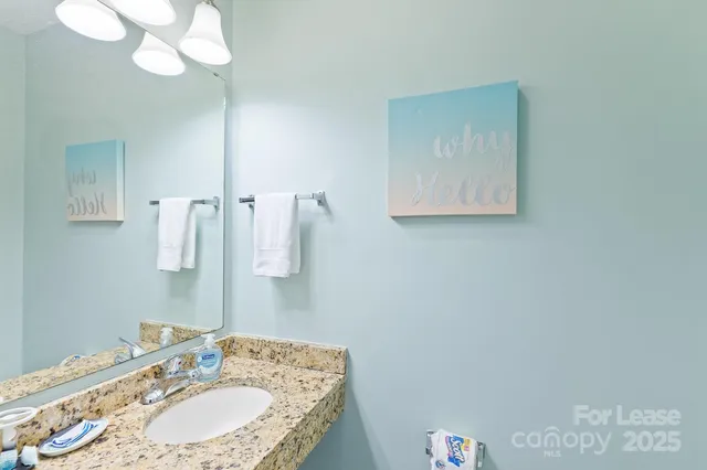 a bathroom with a granite countertop sink a mirror and vanity