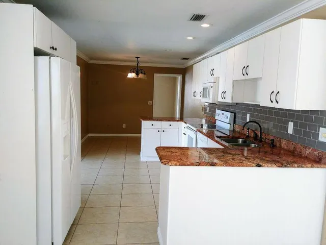a kitchen with stainless steel appliances granite countertop a sink and a refrigerator