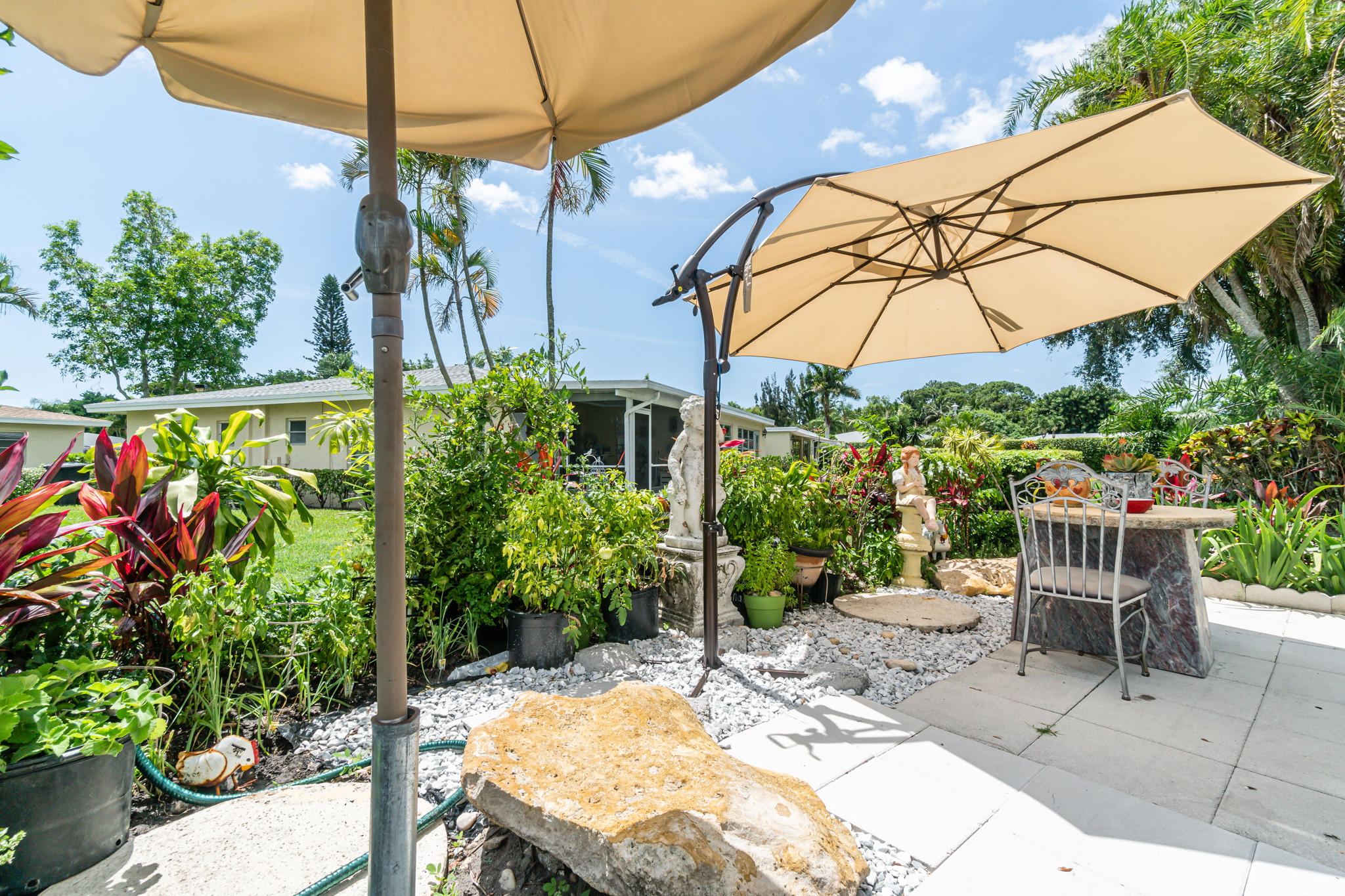 13831 Vía Flora, Unit A Delray Beach, FL 33484 - Photo 24 of 47 a view of a patio with table and chairs under an umbrella