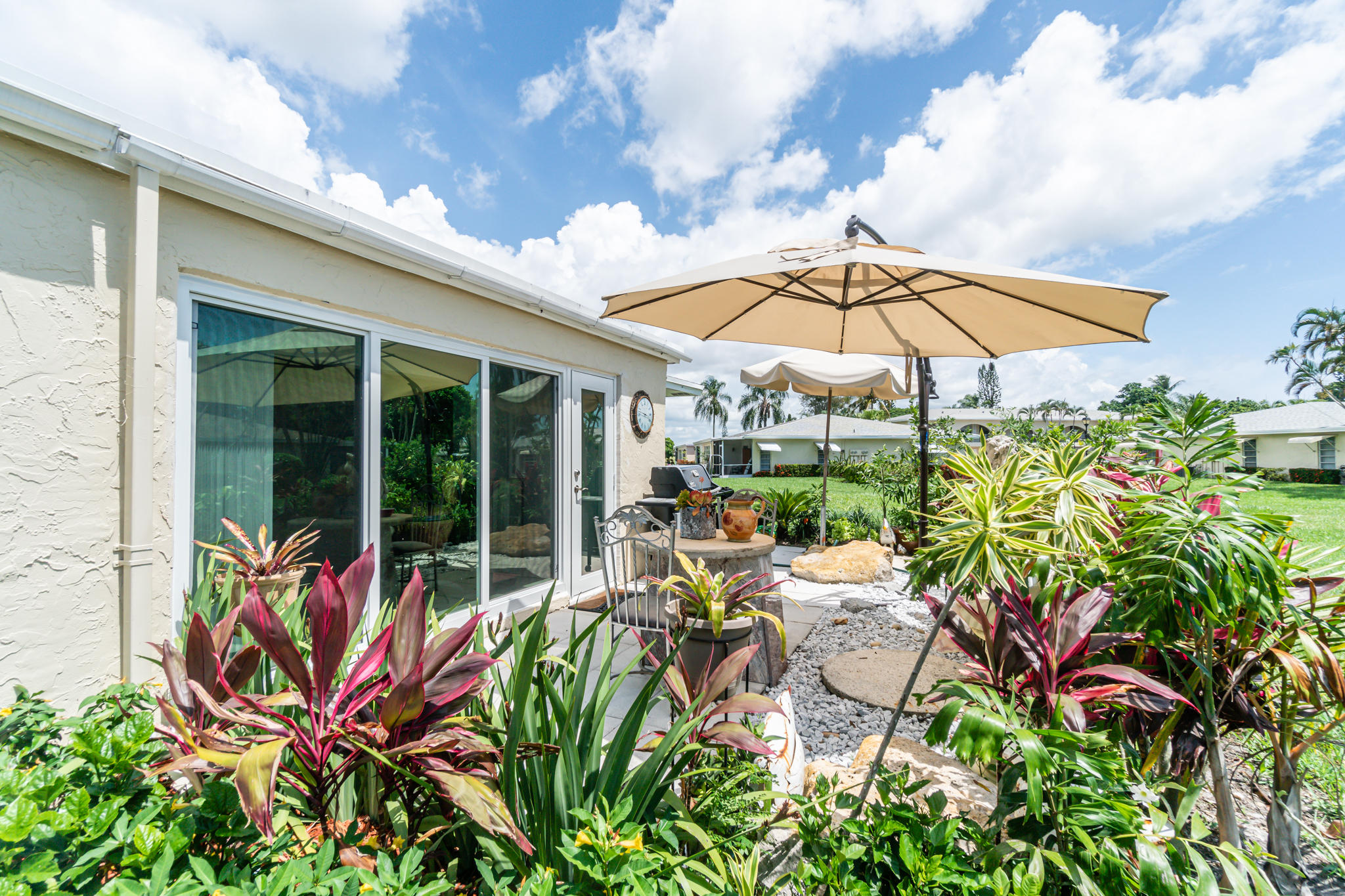 13831 Vía Flora, Unit A Delray Beach, FL 33484 - Photo 25 of 47 a view of a patio with table and chairs under an umbrella