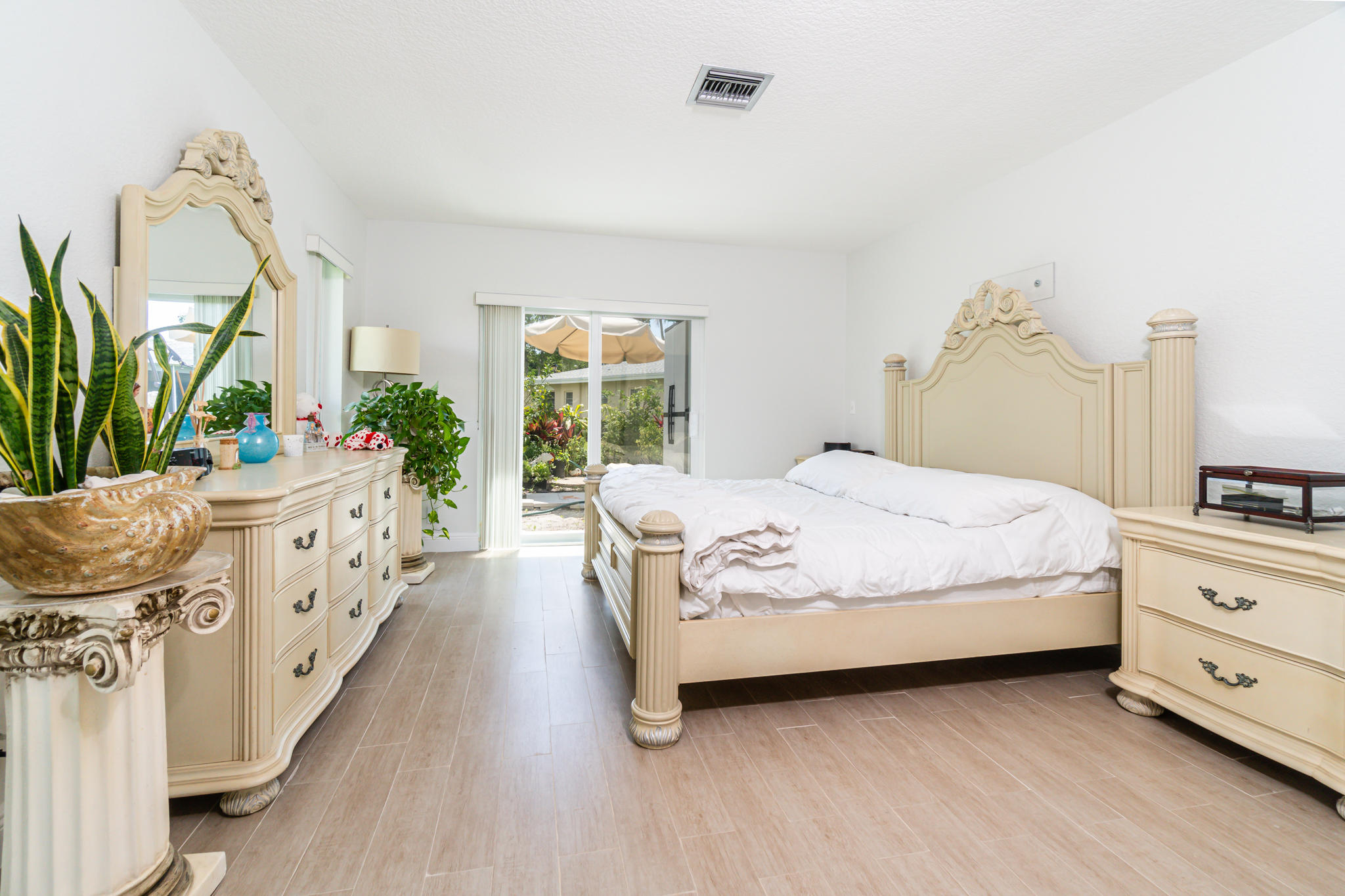 13831 Vía Flora, Unit A Delray Beach, FL 33484 - Photo 4 of 47 a spacious bedroom with a bed and a potted plant