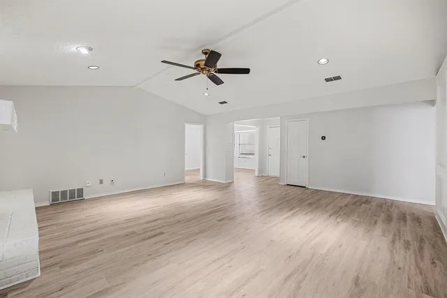 a view of empty room with wooden floor and ceiling fan