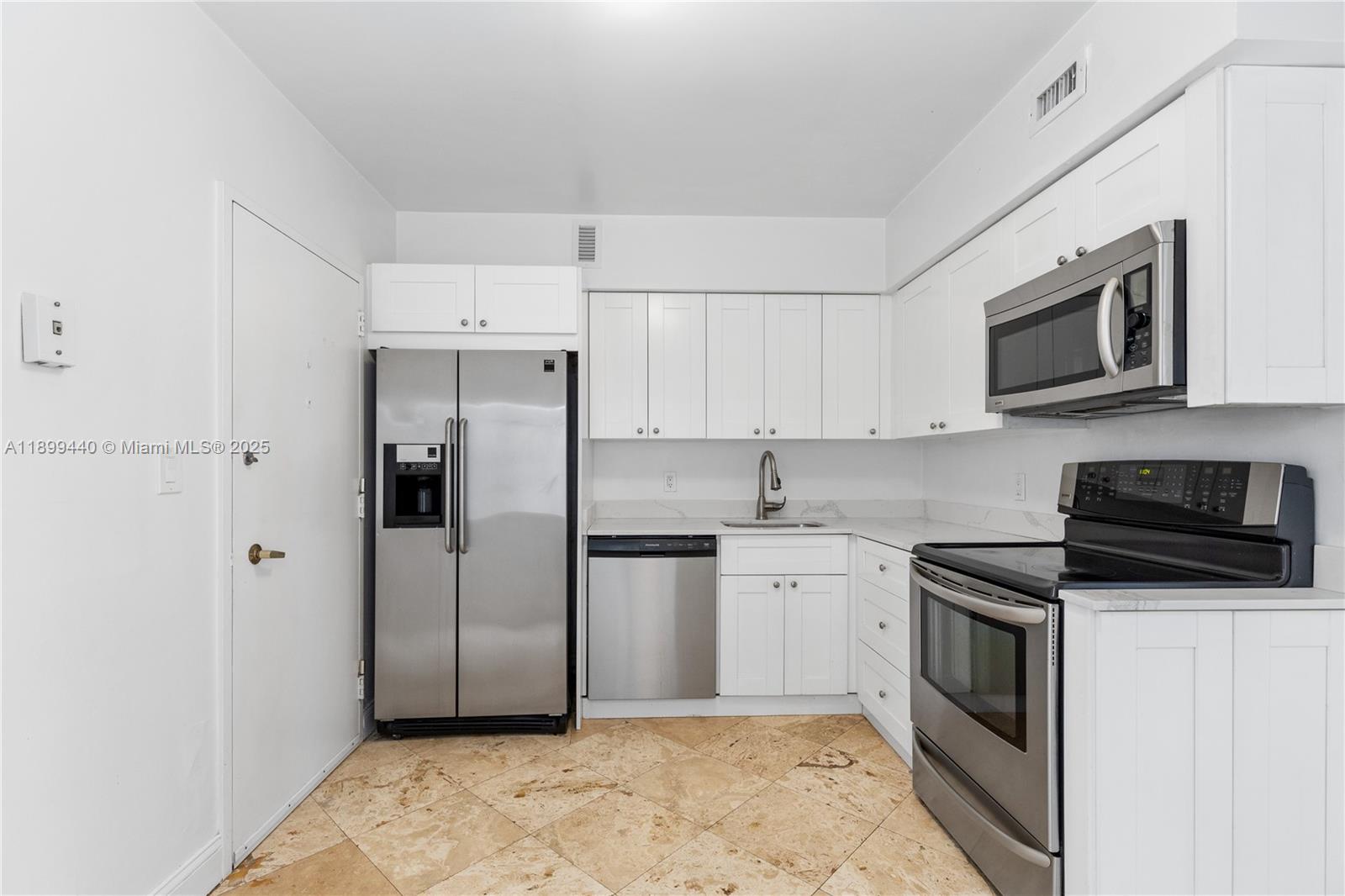 5700 Collins Avenue, Unit 10D Miami Beach, FL 33140 - Photo 13 of 47 a kitchen with stainless steel appliances granite countertop a refrigerator stove a sink and microwave