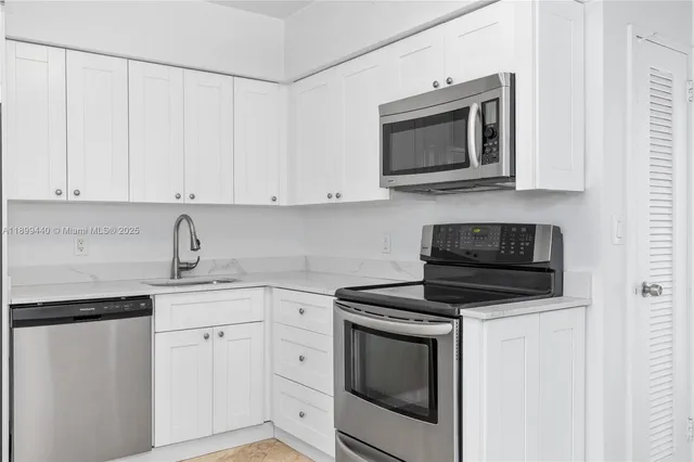 a kitchen with white cabinets and stainless steel appliances