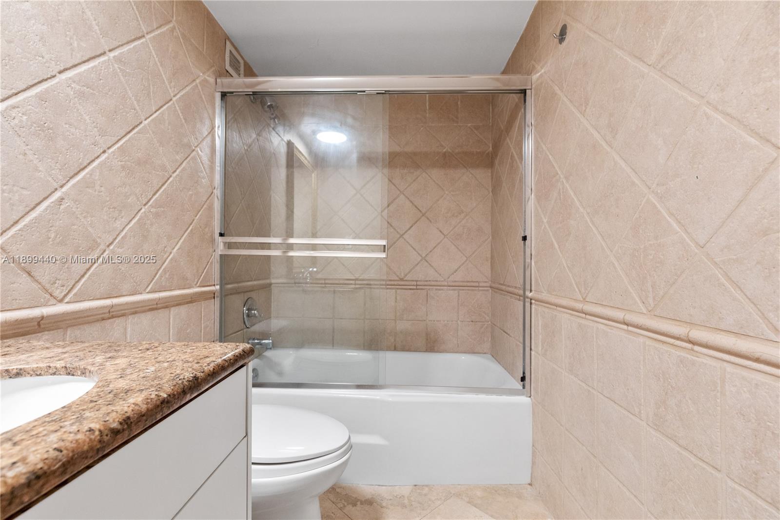5700 Collins Avenue, Unit 10D Miami Beach, FL 33140 - Photo 24 of 47 a bathroom with a granite countertop bathtub shower sink and toilet