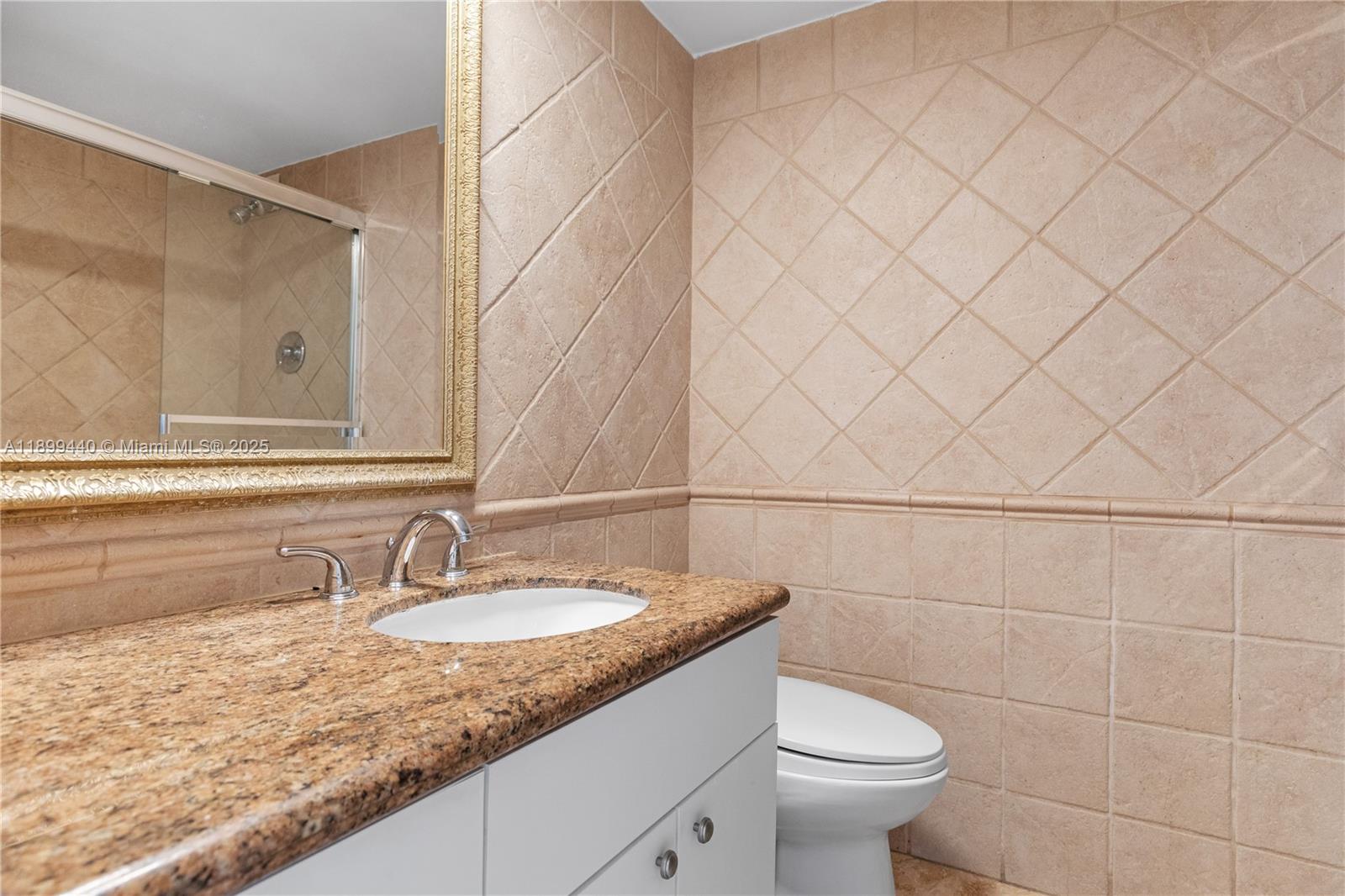 5700 Collins Avenue, Unit 10D Miami Beach, FL 33140 - Photo 27 of 47 a bathroom with a granite countertop sink a toilet and a mirror