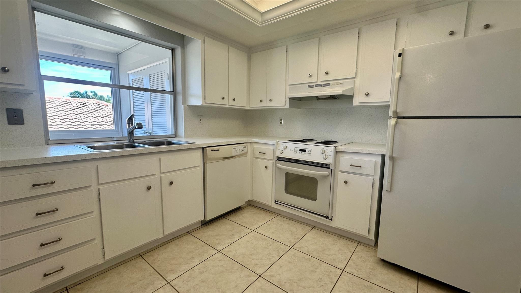 1900 Northeast 29th Street, Unit 2C Lighthouse Point, FL 33064 - Photo 2 of 21 a kitchen with white cabinets and white appliances
