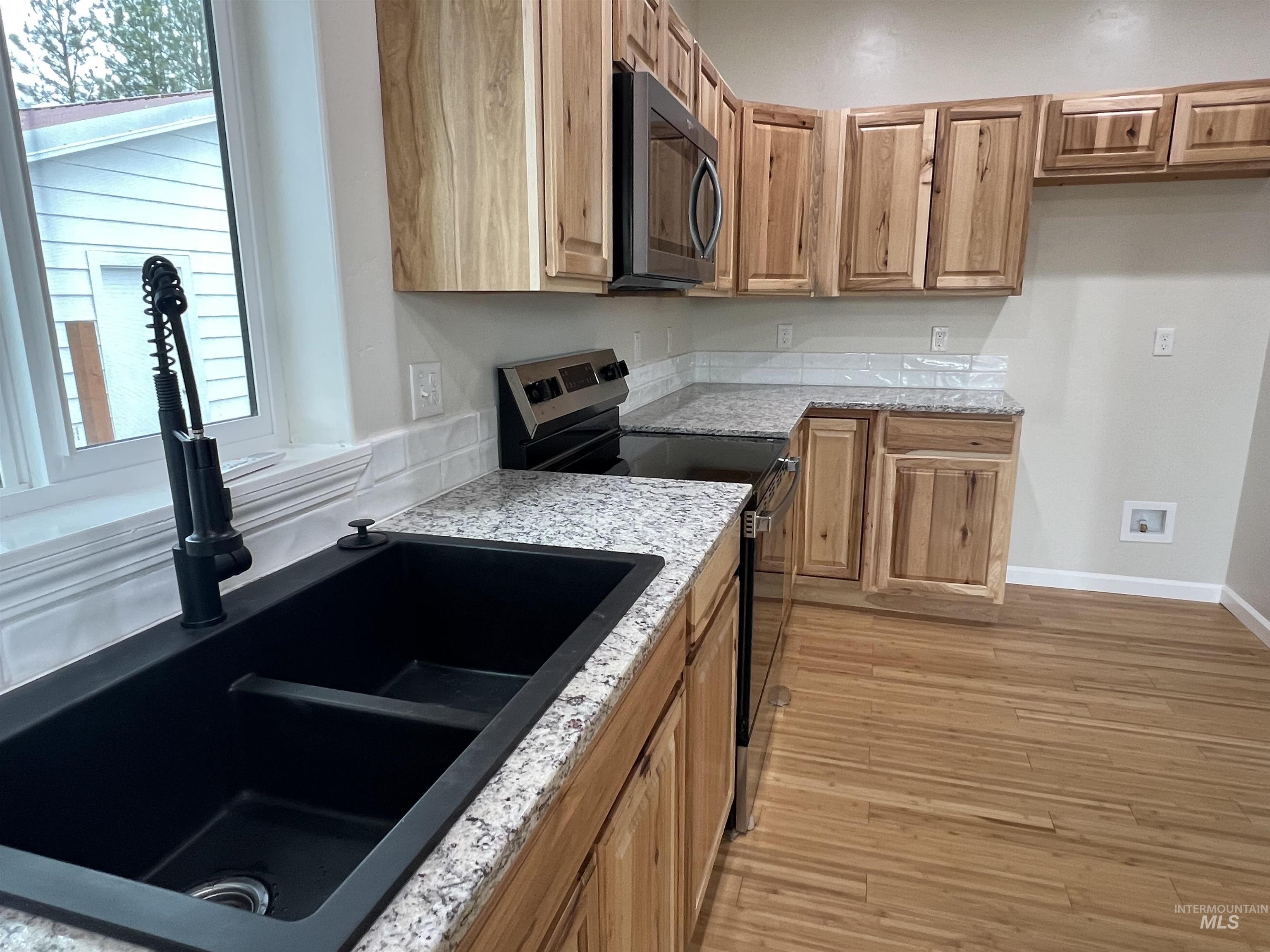 405 North Fairfield Street Council, ID 83612 - Photo 11 of 25 Kitchen with black appliances, plenty of natural light, light wood finished floors, and light stone countertops