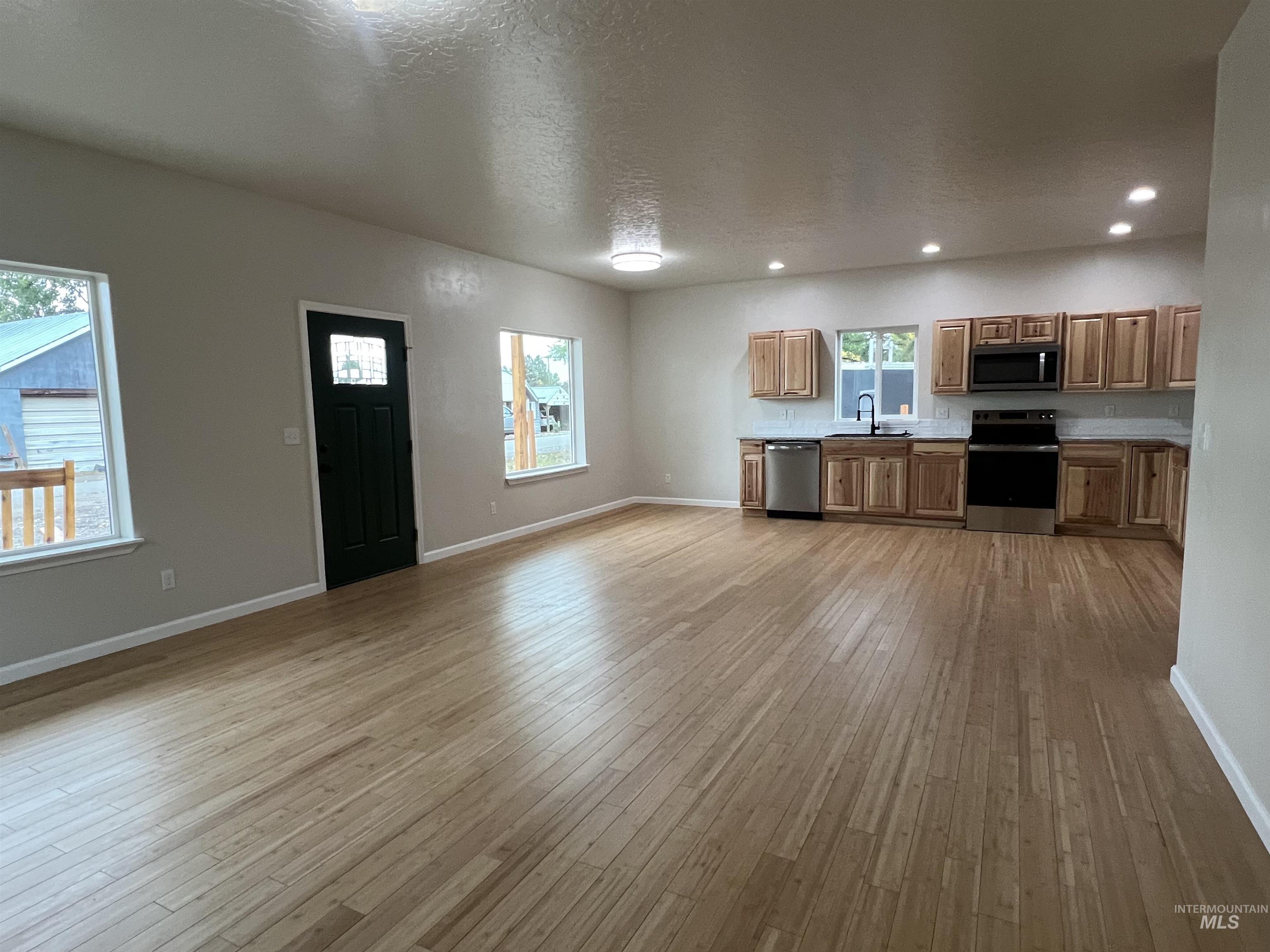 405 North Fairfield Street Council, ID 83612 - Photo 5 of 25 Kitchen featuring appliances with stainless steel finishes, brown cabinets, a textured ceiling, light countertops, and light wood-type flooring