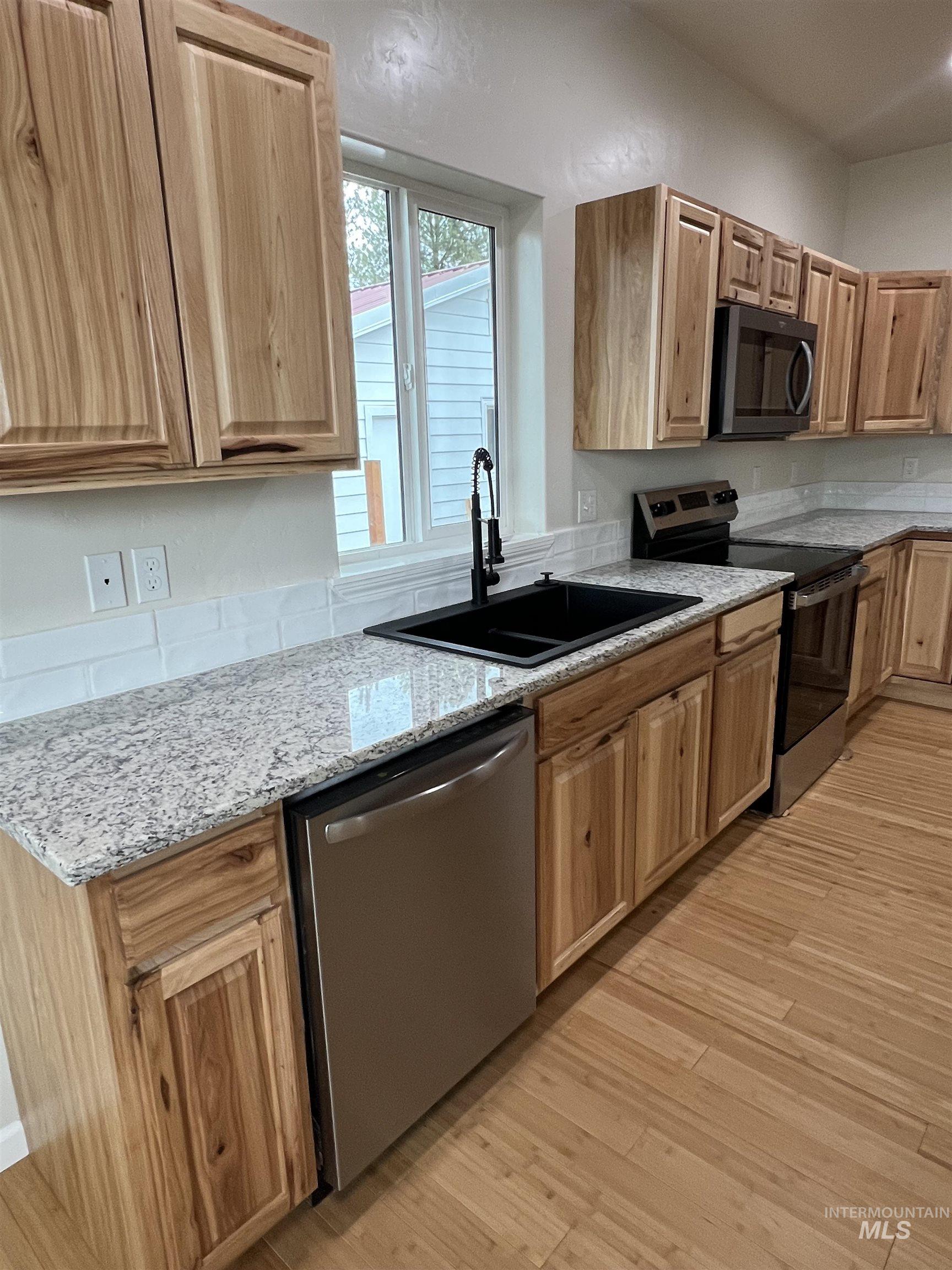 405 North Fairfield Street Council, ID 83612 - Photo 9 of 25 Kitchen featuring appliances with stainless steel finishes, light stone countertops, and light wood-style floors