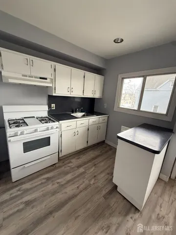 a kitchen with stainless steel appliances a white stove top oven cabinets and a wooden floor
