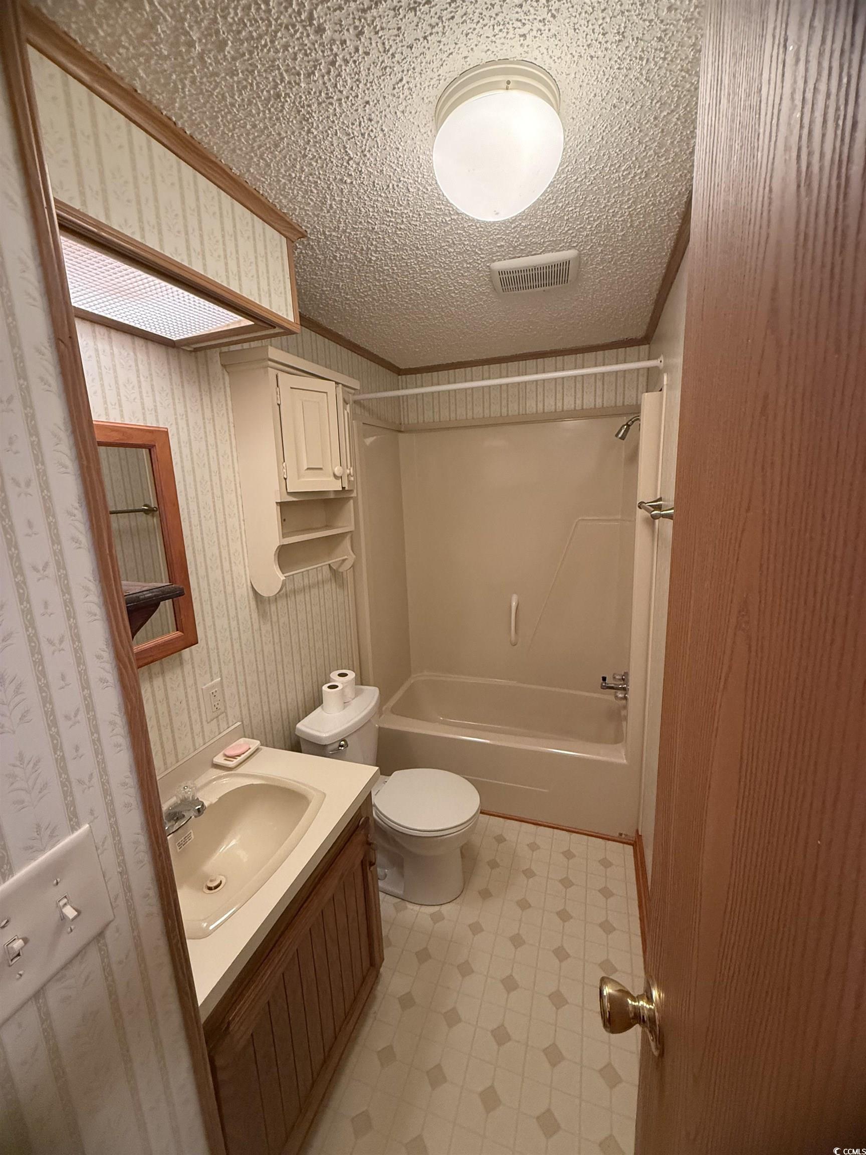 8 Buccaneer Street Murrells Inlet, SC 29576 - Photo 25 of 28 Bathroom with vanity, shower / bathtub combination, wallpapered walls, and a textured ceiling