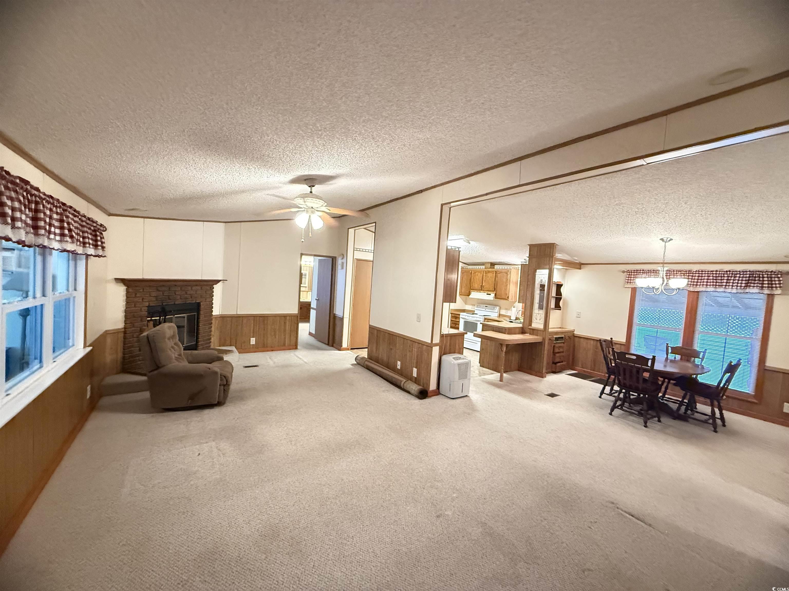 8 Buccaneer Street Murrells Inlet, SC 29576 - Photo 8 of 28 Living area with wood walls, wainscoting, a textured ceiling, light carpet, and a fireplace