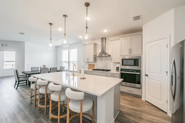 a kitchen with stainless steel appliances and wooden floor