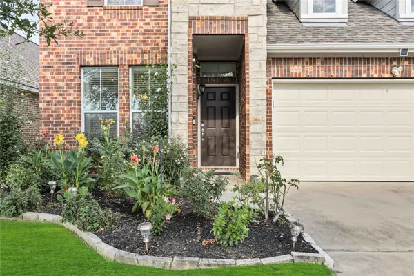 a view of a house with brick walls and a yard with plants