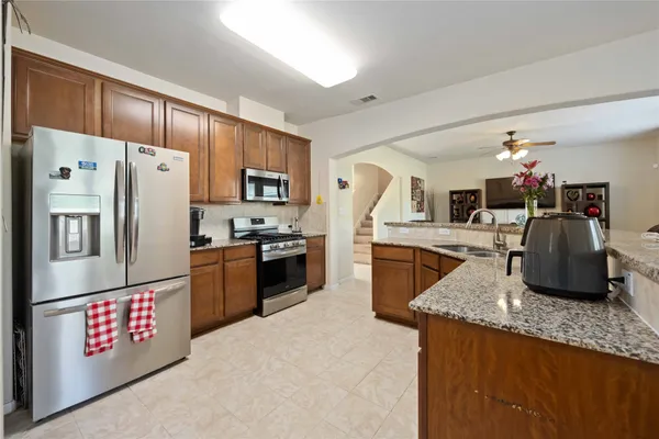 a kitchen with granite countertop a refrigerator a stove a sink a dining table and chairs