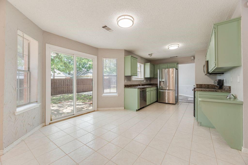 5610 Eagle Rock Road Arlington, TX 76017 - Photo 12 of 33 Kitchen and dining area featuring light green cabinetry, stainless steel appliances, dark countertops, and tile flooring