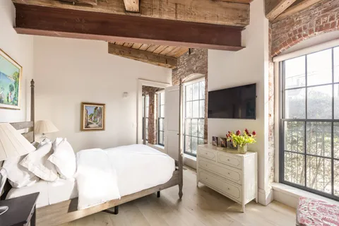 a bedroom with a bed potted plant on the dresser and a window