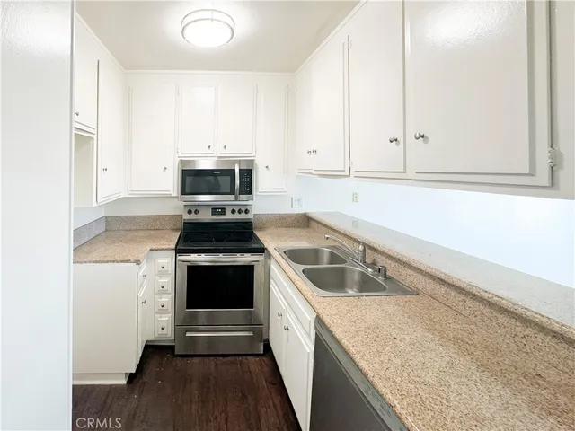 a kitchen with granite countertop a stove and white cabinets