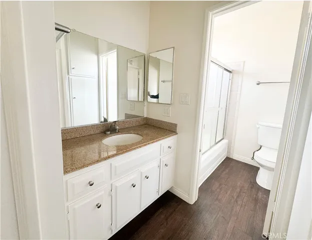 a bathroom with a granite countertop sink toilet and mirror