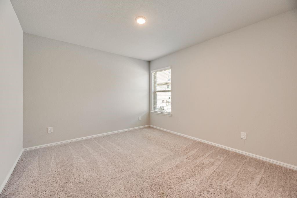 14216 Aberavon Drive Pilot Point, TX 76258 - Photo 16 of 19 Neutral-toned room featuring light beige carpeting, white baseboards, and a single window with horizontal blinds