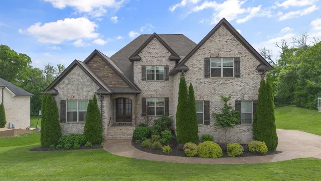 a view of yellow house with a yard and potted plants