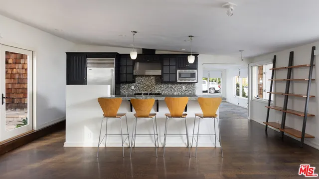 a view of kitchen island with stainless steel appliances granite countertop furniture and a refrigerator