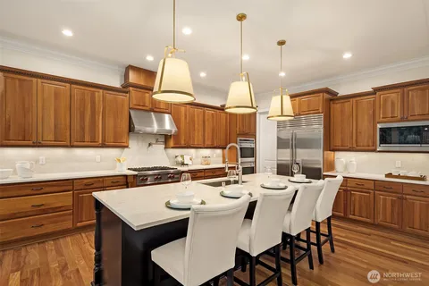 a kitchen with a stove a kitchen island a sink cabinets and wooden floor