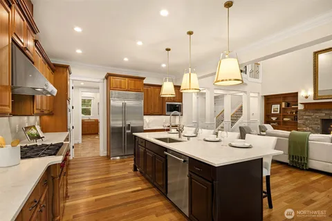 a kitchen with stainless steel appliances granite countertop a sink a stove and a wooden floor