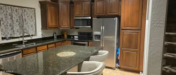 a kitchen with stainless steel appliances granite countertop a refrigerator a sink a stove and a microwave oven