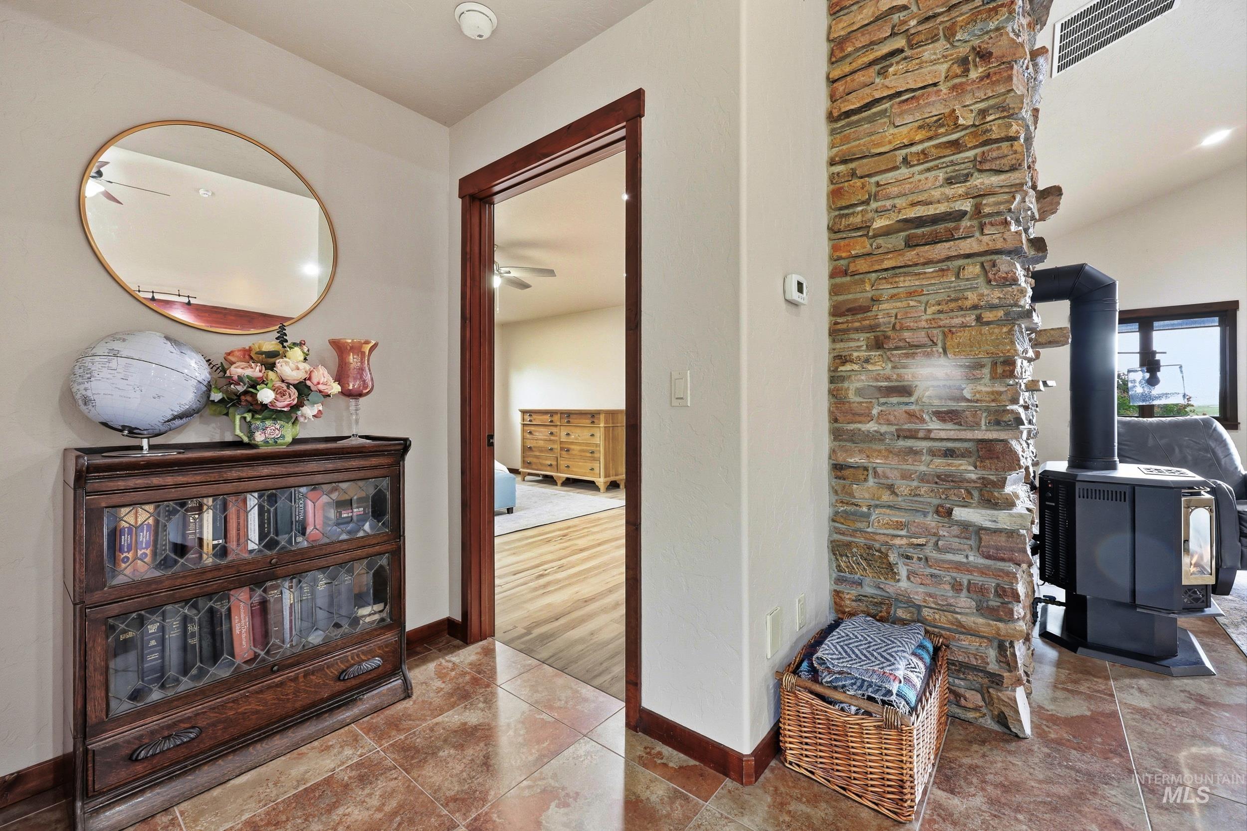 339 Airport Road Weiser, ID 83672 - Photo 21 of 49 Foyer featuring tile flooring, a stone accent wall, and a wood stove with a black stovepipe