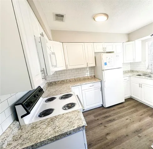 a kitchen with a refrigerator a stove a sink and a wooden floor