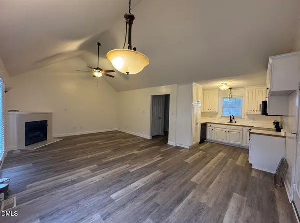 a view of a kitchen with a sink and dishwasher a fireplace with wooden floor
