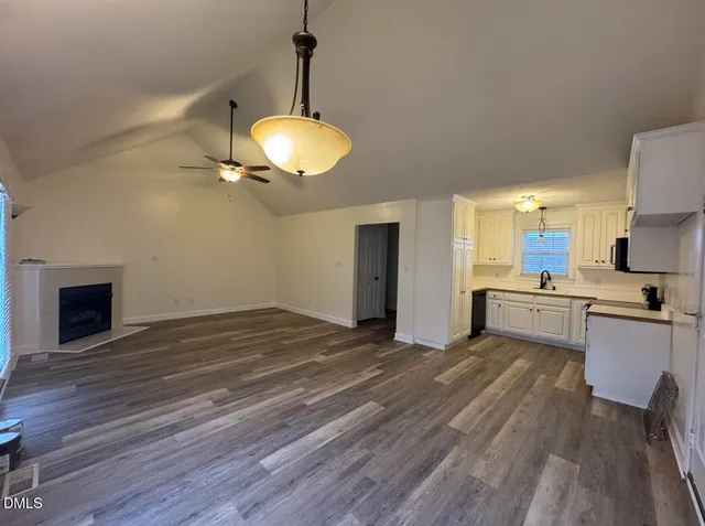 a view of a kitchen with a sink and dishwasher a fireplace with wooden floor