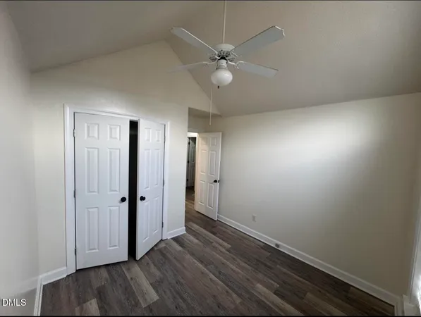 an empty room with wooden floor and fan