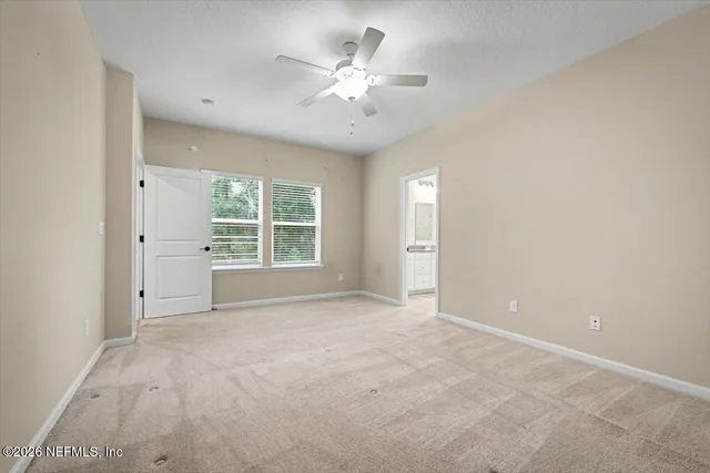 an empty room with windows and ceiling fan
