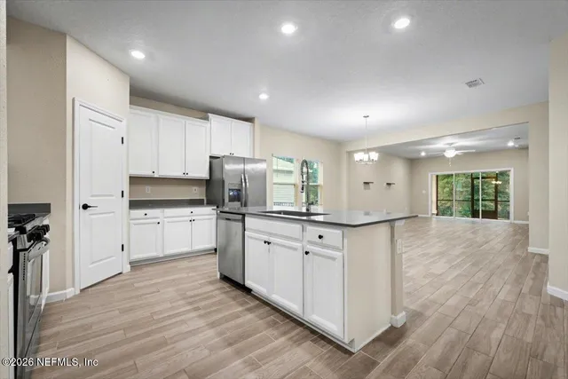 a kitchen with stainless steel appliances a refrigerator a stove top oven and white walls