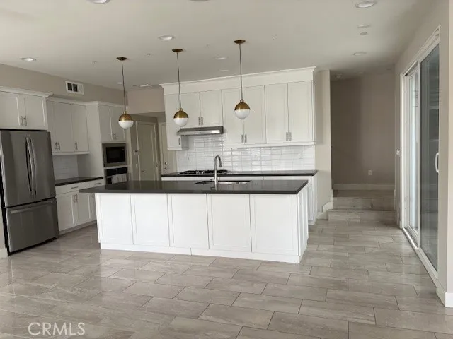 a kitchen with kitchen island a counter top space a sink and refrigerator