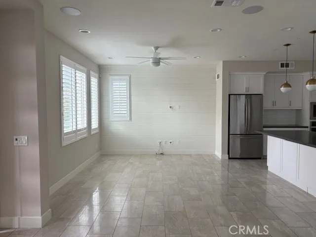 an empty room with windows and refrigerator