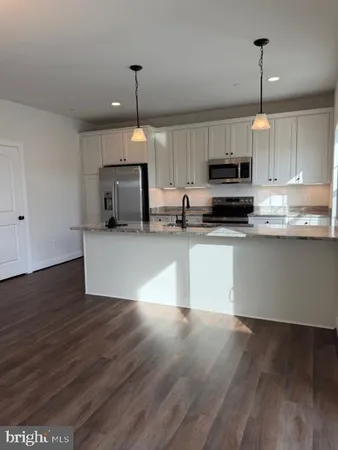 a kitchen with kitchen island granite countertop a sink cabinets and wooden floor