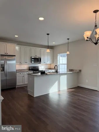 a kitchen with stainless steel appliances wooden floor and a refrigerator
