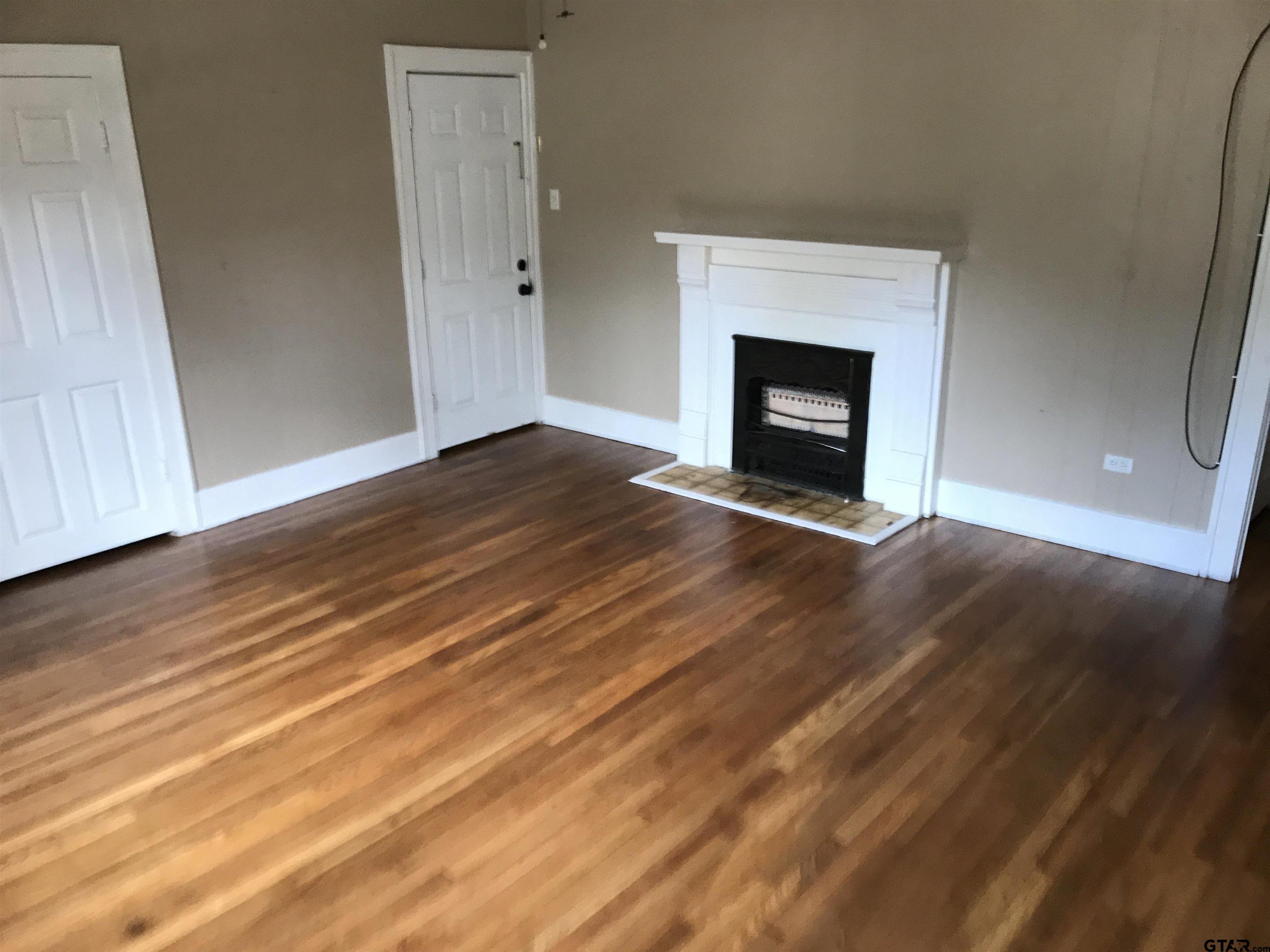 208 West Phillips Street, Unit 200 Tyler, TX 75701 - Photo 2 of 11 a view of empty room with wooden floor and fireplace